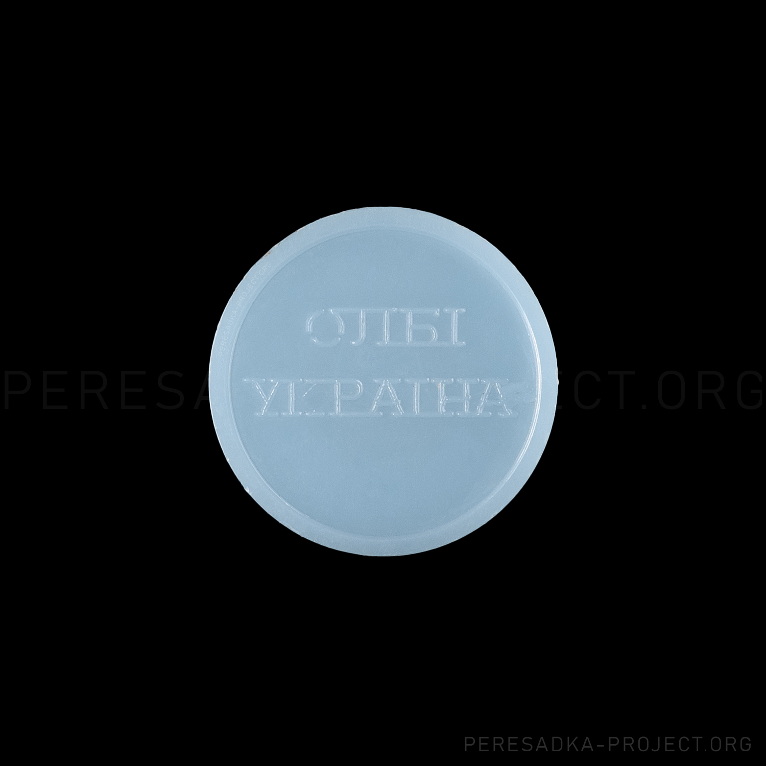 Фото жетона Киев олби. Реверс на чёрном фоне. Непрозрачный пластик диаметром 25 мм, Киев, Украина. Жетон из проекта «Пересадка» – частного каталога-музея по теме метро.